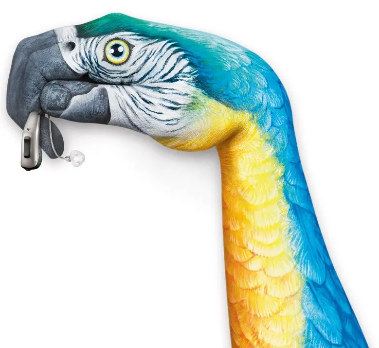 Un braccio e mano colorati che sembrano un pappagallo che tiene un apparecchio acustico col becco.